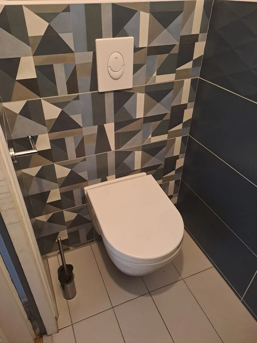 Un WC suspendu blanc devant un carrelage géométrique gris
